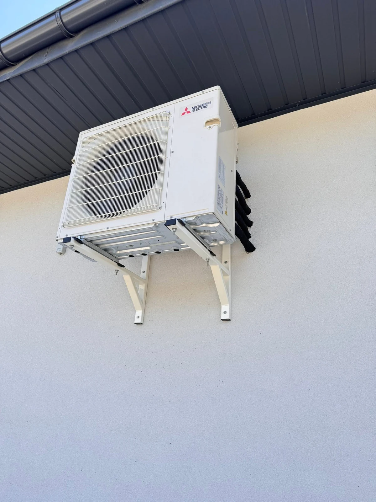 Jednostka zewnętrzna klimatyzacji Mitsubishi Electric na konsolach pod okapem